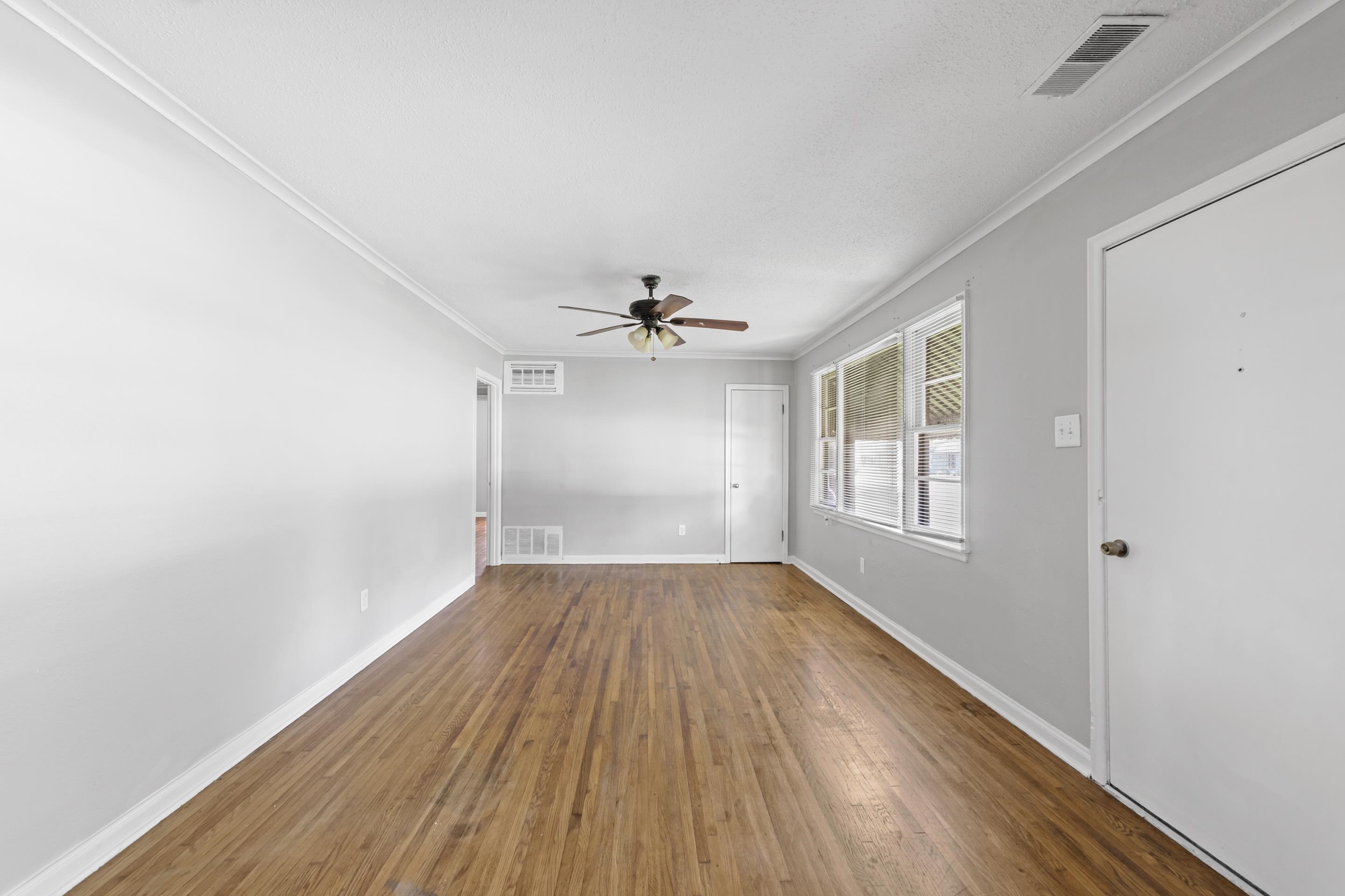 1418 South Perkins Road Memphis, TN 38117 - Photo 9 of 21 an empty room with wooden floor ceiling fan and windows