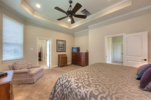 a spacious bedroom with a large bed and ceiling fan