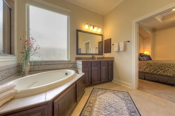 a spacious bathroom with a tub sink and mirror
