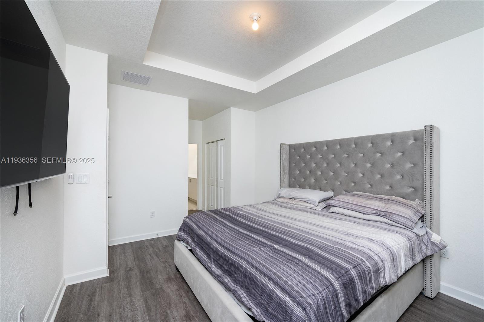 23061 Southwest 128th Place Miami, FL 33177 - Photo 15 of 28 a bedroom with a bed and a flat tv screen on a dresser