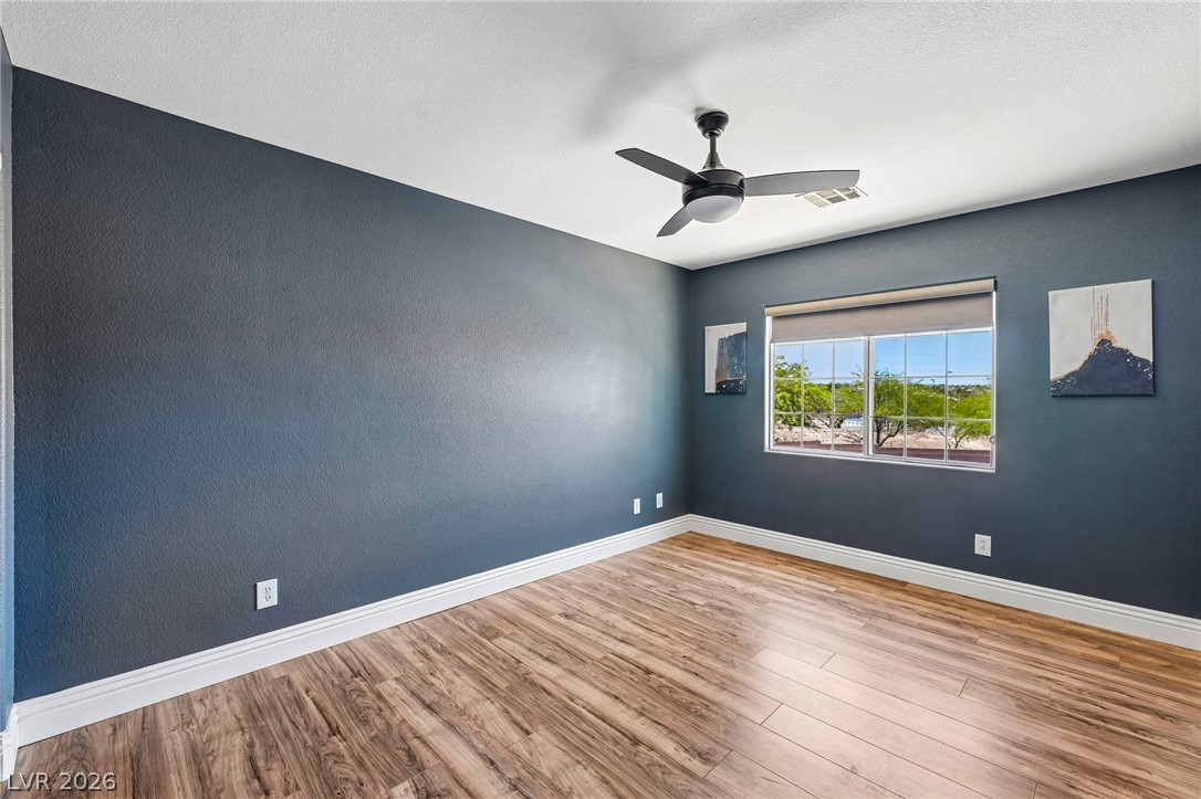 1176 Butternut Ranch Court Henderson, NV 89052 - Photo 26 of 60 A well-lit bedroom features durable hardwood flooring and an overhead ceiling fan for comfort.