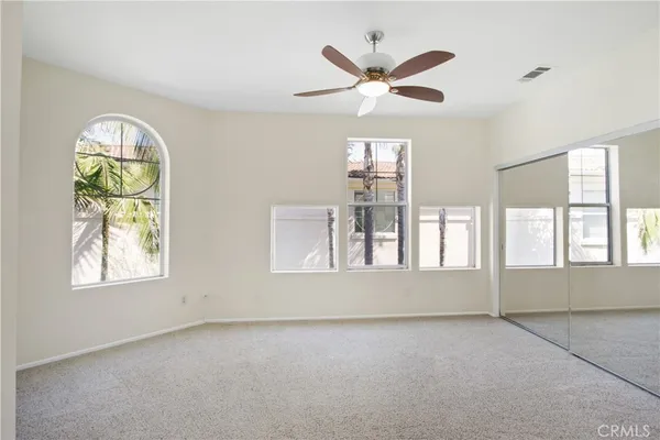 an empty room with windows and ceiling fan