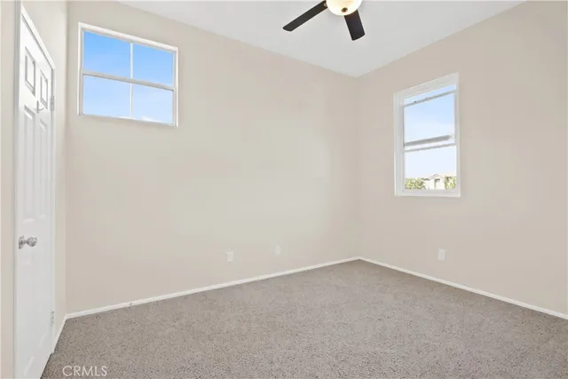 an empty room with windows and fan