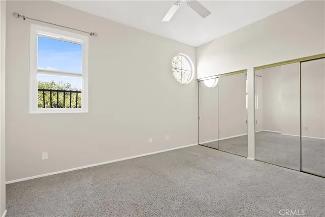 an empty room with windows and fan