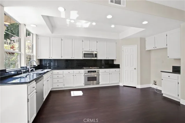 a kitchen with stainless steel appliances granite countertop a stove a sink and white cabinets