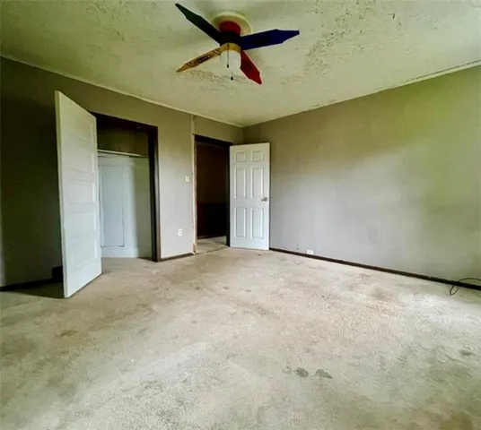 an empty room with a ceiling fan and window
