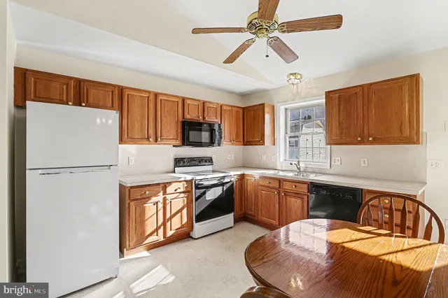 a kitchen with stainless steel appliances granite countertop a sink a stove a refrigerator cabinets a dining table and chairs