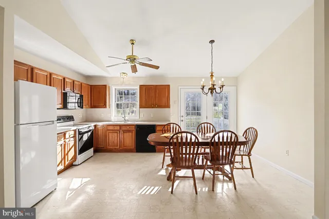 a kitchen with stainless steel appliances granite countertop a dining table chairs and a refrigerator