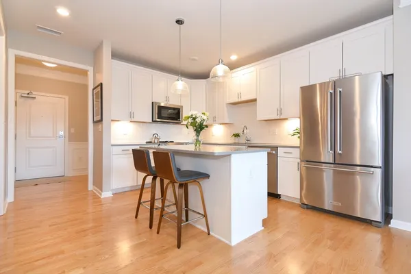 a kitchen with stainless steel appliances a refrigerator a stove a sink a dining table and chairs with wooden floor