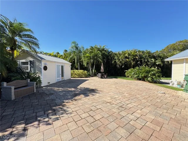 a view of a white house with a yard and potted plants