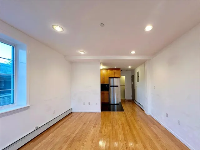 a view of an empty room with window and wooden floor