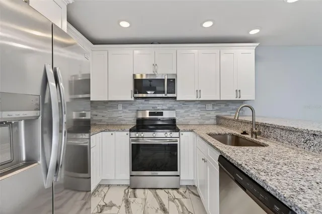 a kitchen with stainless steel appliances granite countertop a sink stove and refrigerator