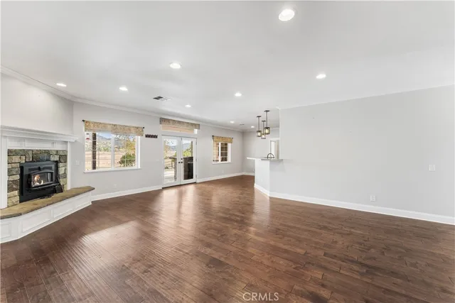 an empty room with wooden floor fireplace and windows