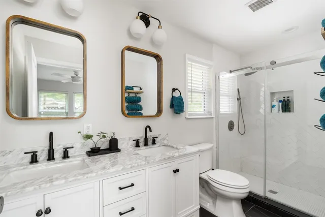 a bathroom with double vanity sink toilet and shower