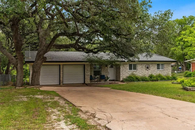 a front view of a house with a garden and trees
