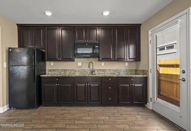 a kitchen with granite countertop wooden cabinets and a refrigerator