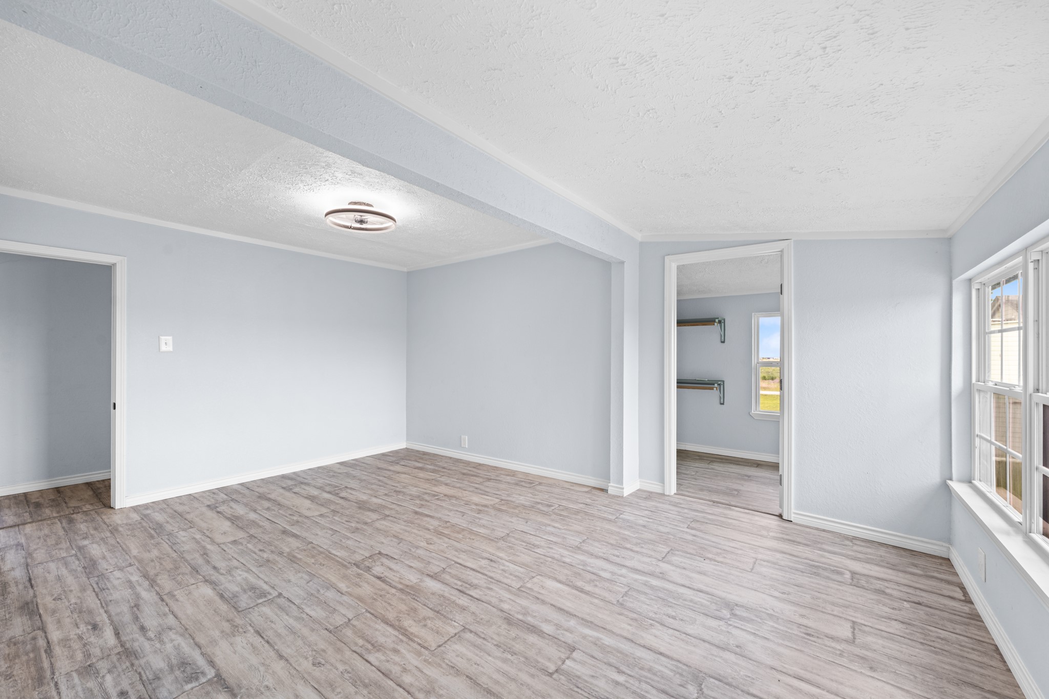 2534 Bastrop Angleton, TX 77515 - Photo 21 of 50 Expansive primary bedroom featuring updated wood-look flooring, soft neutral finishes, and abundant natural light from multiple windows. The spacious layout offers direct access to a large walk-in closet area, creating a comfortable and functional private retreat.