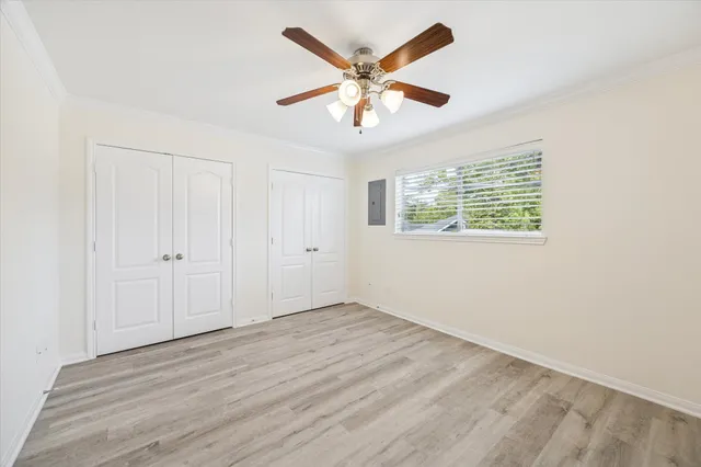 an empty room with wooden floor ceiling fan and windows