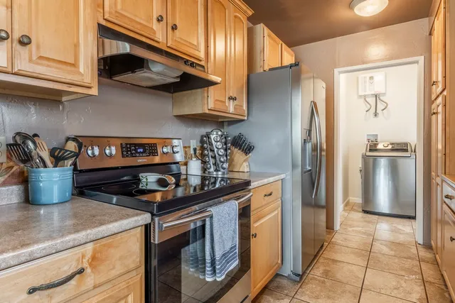 a kitchen with stainless steel appliances granite countertop a refrigerator a stove and a sink