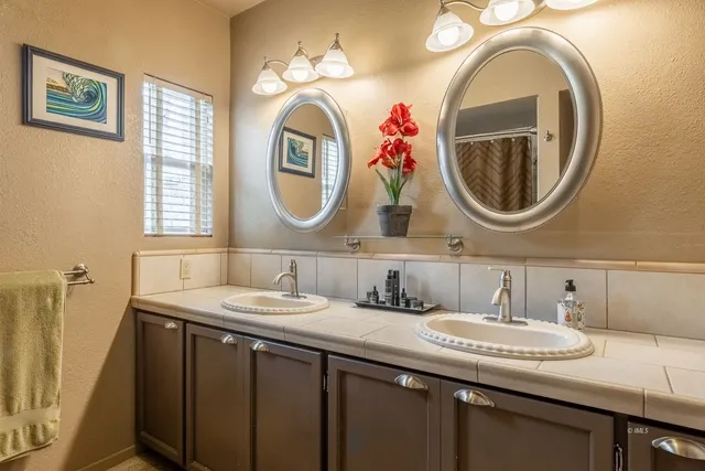 a bathroom with a granite countertop double vanity and a mirror