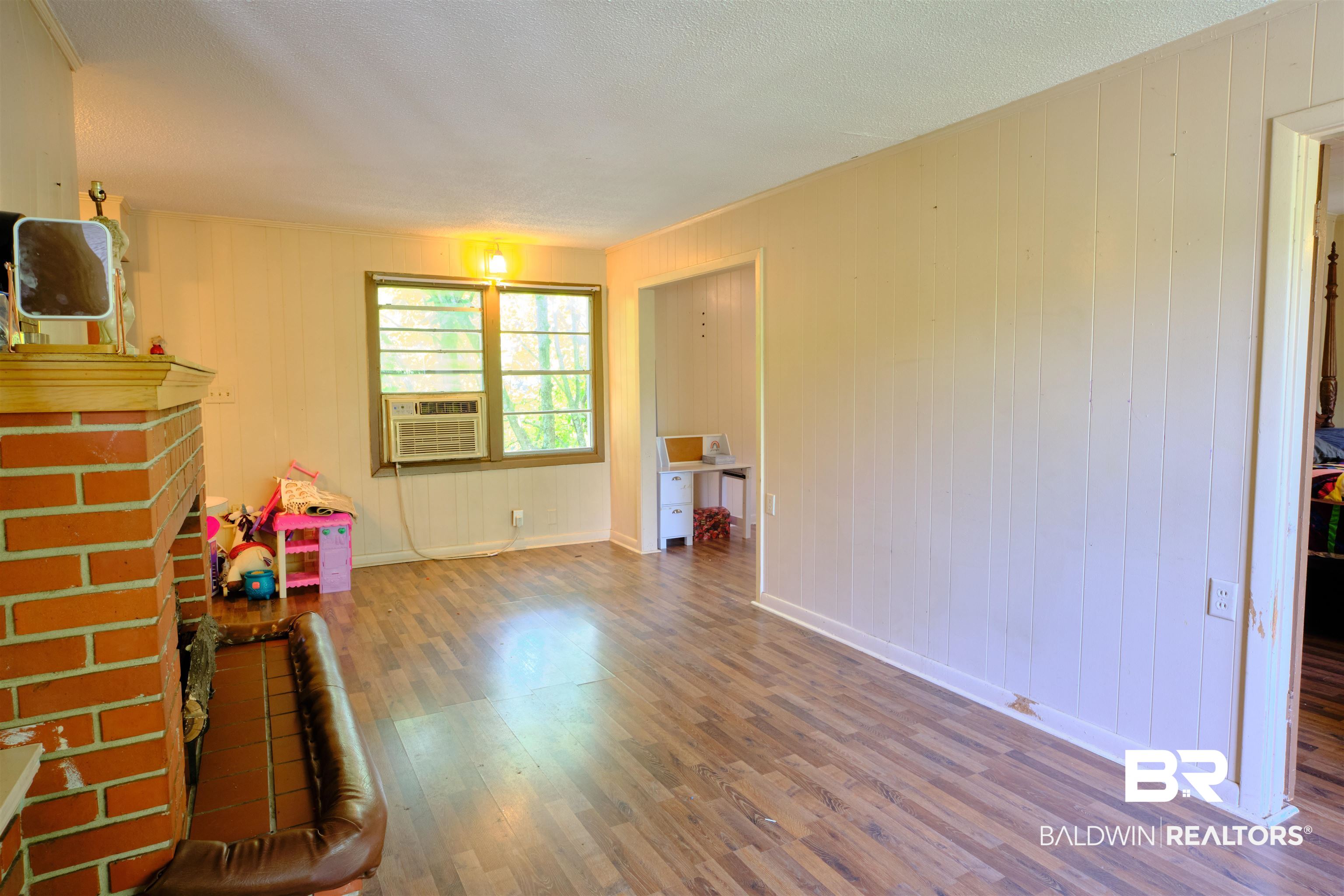 101 West Horner Street Atmore, AL 36502 - Photo 38 of 38 Unfurnished living room featuring a brick fireplace, cooling unit, hardwood / wood-style floors, and a textured ceiling