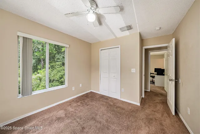 an empty room with windows and ceiling fan