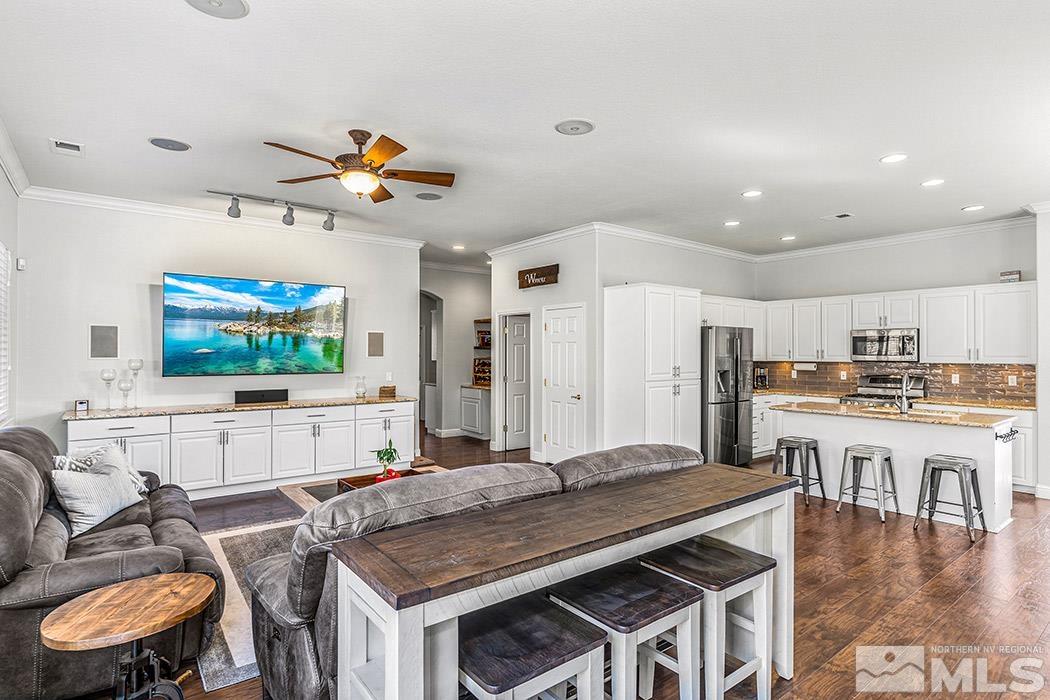 10589 Twin Bridges Way Reno, NV 89521 - Photo 11 of 34 a kitchen with stainless steel appliances granite countertop a stove a refrigerator a kitchen island a dining table and chairs with wooden floor