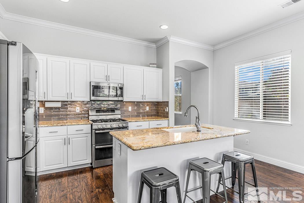 10589 Twin Bridges Way Reno, NV 89521 - Photo 8 of 34 a kitchen with stainless steel appliances granite countertop a table chairs sink and cabinets