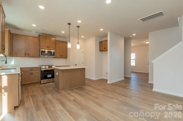 a large kitchen with stainless steel appliances granite countertop a large counter top a sink and a stove