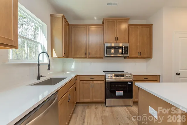 a kitchen with stainless steel appliances granite countertop a sink stove and cabinets