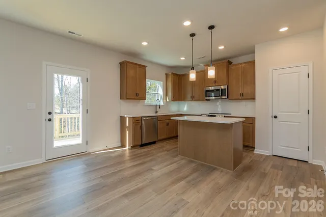 a large kitchen with kitchen island a sink dishwasher a stove and a refrigerator with wooden floor