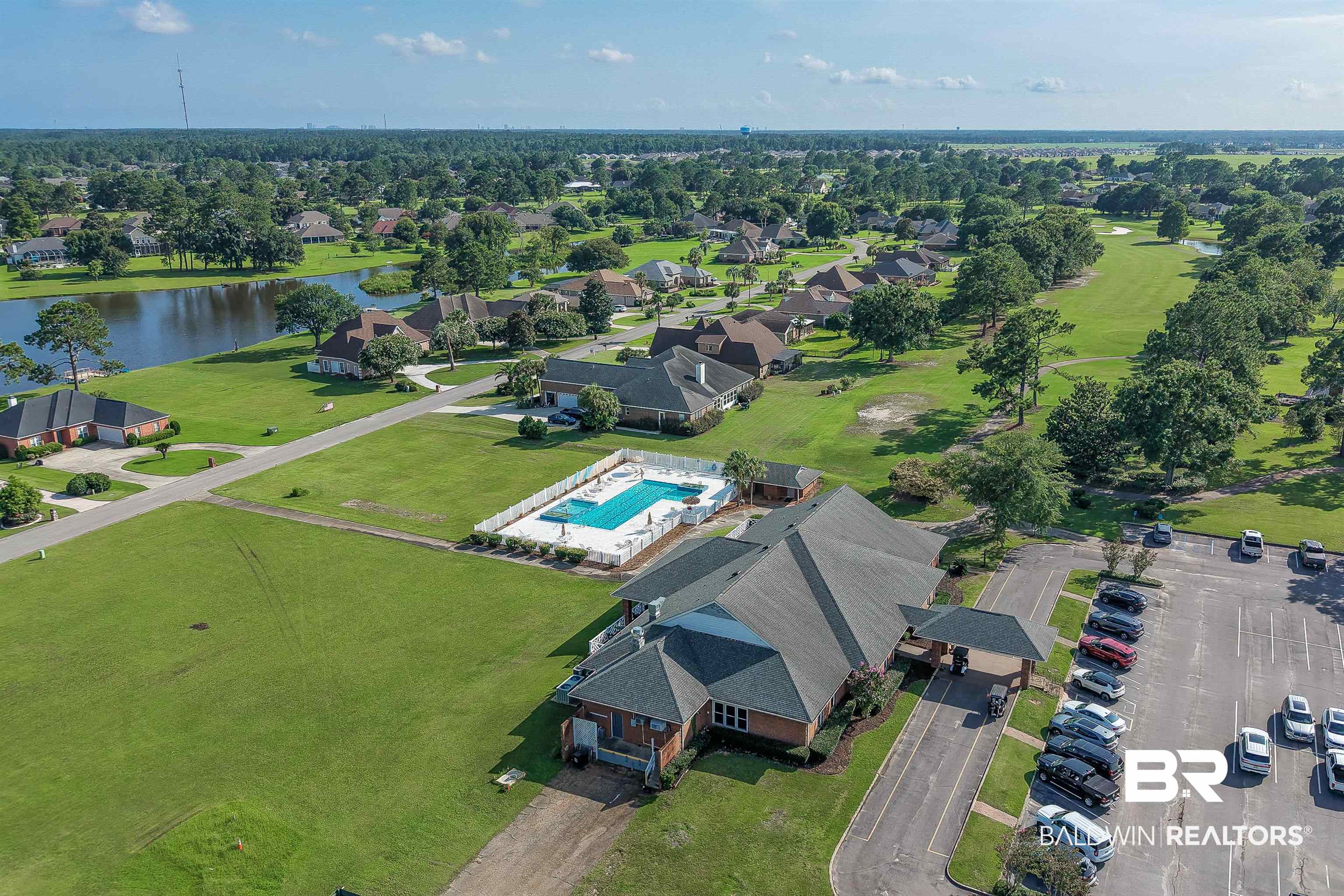 22685 County Road 12 Foley, AL 36535 - Photo 86 of 89 Aerial panorama featuring a community building with a shingled roof, an adjacent swimming pool, and a paved parking area