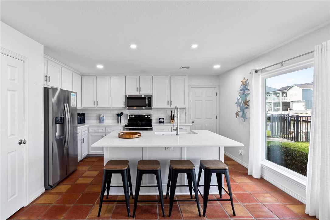 21 Flamingo Road Rockport, TX 78382 - Photo 3 of 30 a kitchen with stainless steel appliances a dining table chairs refrigerator and cabinets