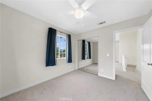 a view of a big room with windows and chandelier fan