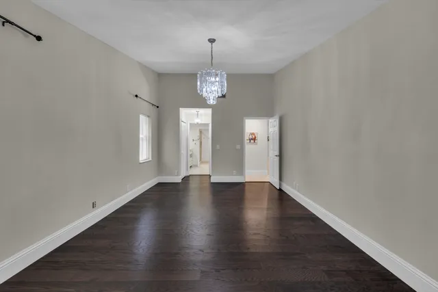a view of an empty room with wooden floor and windows