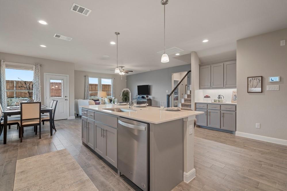 130 Hugo Court Rhome, TX 76078 - Photo 9 of 40 a kitchen with kitchen island a sink a stove a dining table and chairs