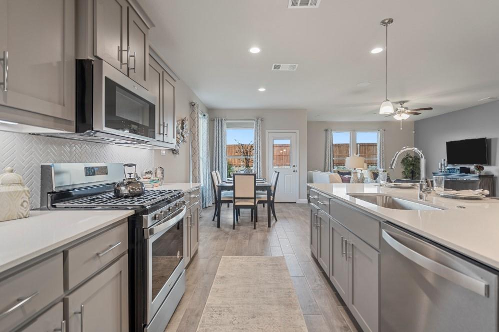 130 Hugo Court Rhome, TX 76078 - Photo 5 of 40 a kitchen with stainless steel appliances a sink stove and cabinets