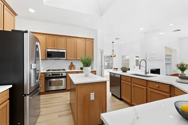 a kitchen with stainless steel appliances granite countertop a sink stove refrigerator and cabinets