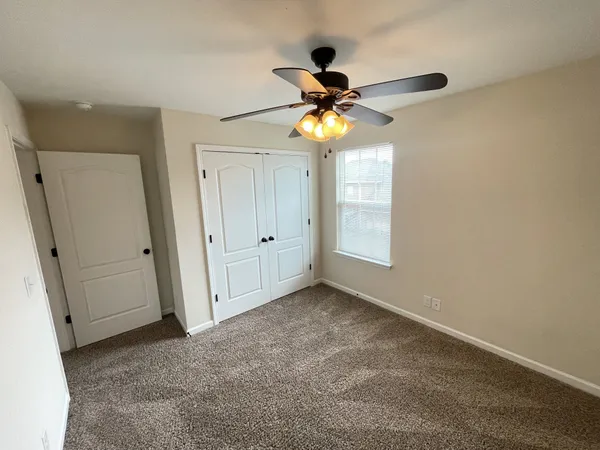 an empty room with a window and a fan