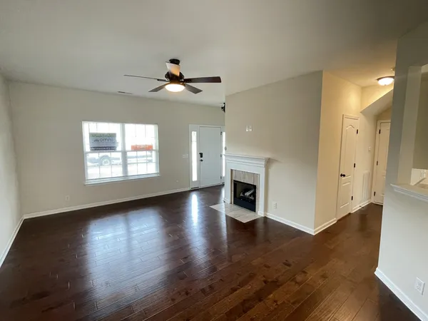 an empty room with wooden floor fireplace and windows