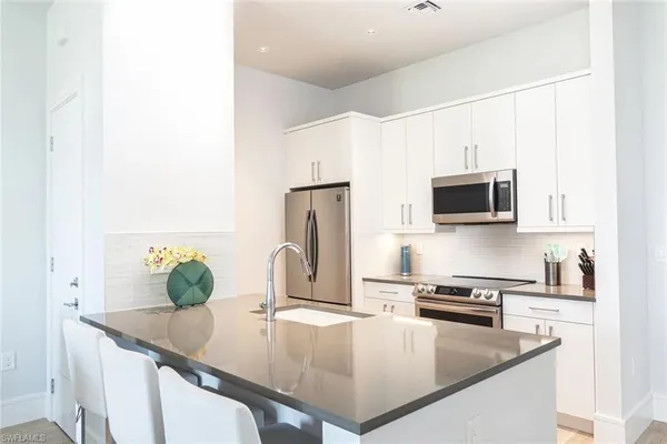 a kitchen with stainless steel appliances a microwave a sink and cabinets