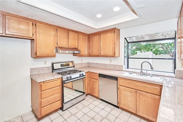 a kitchen with cabinets appliances a sink and a window
