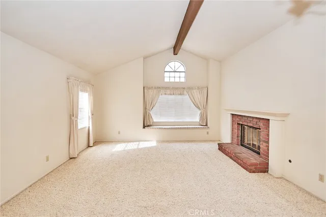a view of an empty room with a window and a kitchen