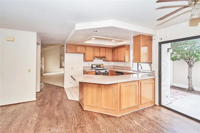 a kitchen with stainless steel appliances granite countertop a stove a sink and a refrigerator with wooden floor