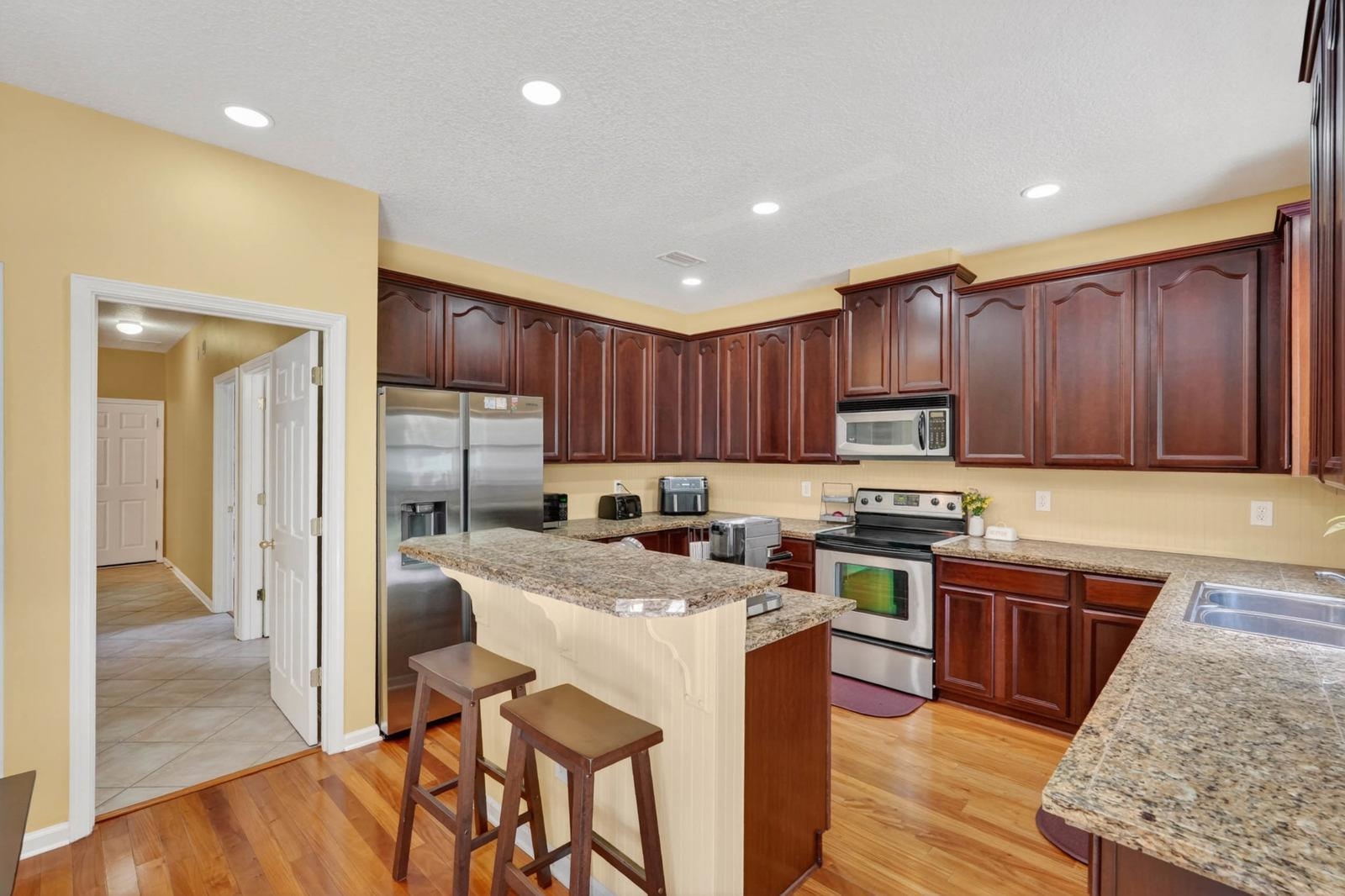 1237 Splendid Ravine Street St. Augustine, FL 32092 - Photo 16 of 62 a kitchen with stainless steel appliances granite countertop wooden cabinets a stove a sink and a refrigerator
