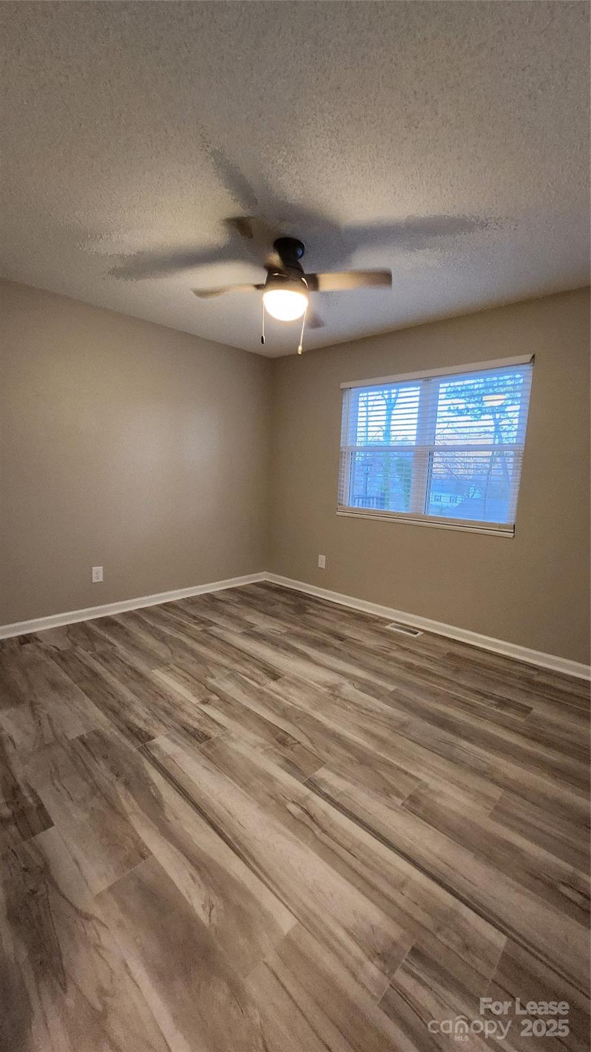 7505 Sarah Drive Denver, NC 28037 - Photo 8 of 13 an empty room with wooden floor ceiling fan and windows