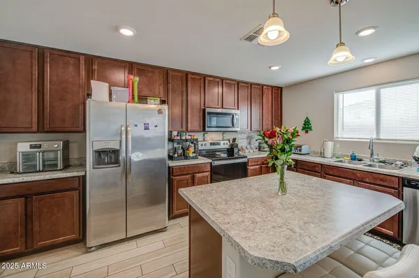 a kitchen with granite countertop stainless steel appliances a refrigerator a stove a sink cabinets and a center island