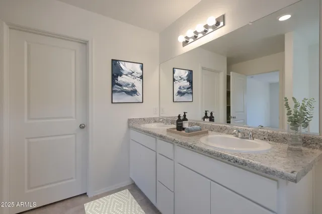 a bathroom with a granite countertop double vanity sink and a mirror