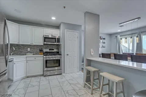 a kitchen with stainless steel appliances a stove a sink a microwave a dining table and chairs