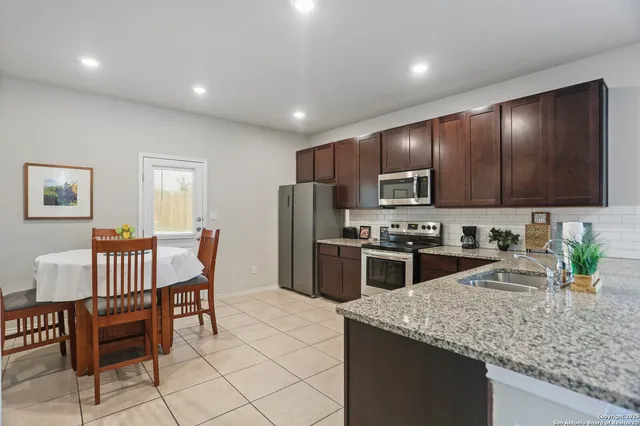 a kitchen with stainless steel appliances granite countertop a stove a sink a microwave a dining table and chairs